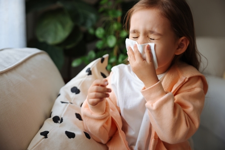 little girl sneezing on couch