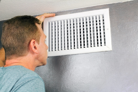 man checking airflow out of air vent