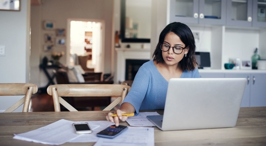 woman at table on computer with calculator