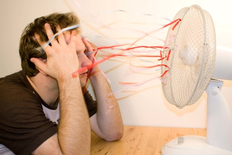 man cooling off in front of fan