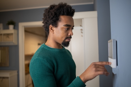 man adjusting thermostat