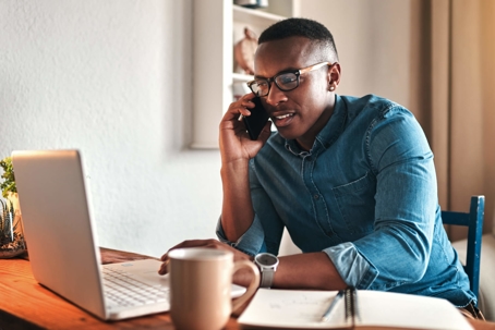 man on phone in front of laptop at home