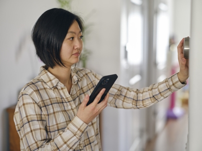 woman syncing smart thermostat with smartphone